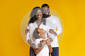 Loving black family with daughter embracing and smiling at camera