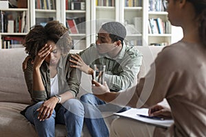 Loving black man comforting crying wife while having family therapy