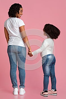 Loving Black Mom And Daughter Holding Hands And Smiling, Rear View