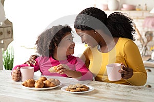 Loving Black Mom And Little Daughter Having Snacks In Kitchen At Home
