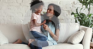 Loving Black mum relax with preschool age daughter talk cuddle