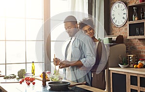 Loving black wife and husband preparing dinner in kitchen