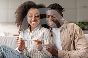 Loving Black Young Couple Holding Positive Pregnancy Test Embracing Indoor