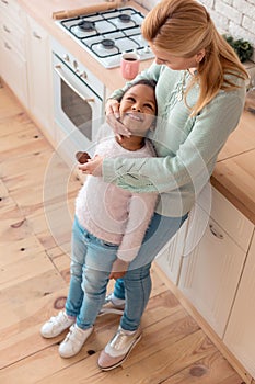 Loving blonde-haired mother hugging her cute little girl