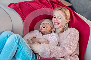 Loving blonde-haired mother hugging her lovely cute girl