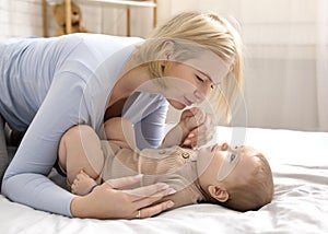 Loving blonde mother caressing her baby boy on bed