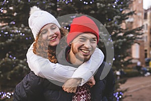 Loving boyfriend and girlfriend are hugging by Christmas tree