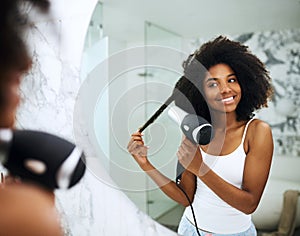 Loving care nourishes luxurious hair. an attractive young woman blowdrying her hair at home.