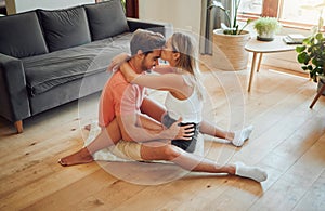 Loving caucasian couple being affectionate and enjoying romantic intimate moment while sitting on living room floor