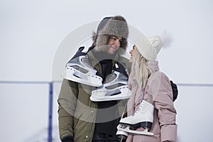 Loving Caucasian Couple On Skatingrink With Ice Skates Posing Together Over a Snowy Winter Landscape Against Fence