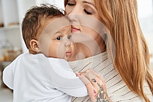 Loving caucasian mother holding adorable african american baby daughter.