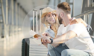 Loving couple in airport using travel app on smartphone