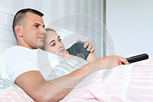 loving couple in bed, watching television together