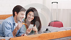 Loving couple booking tickets using phone and credit card