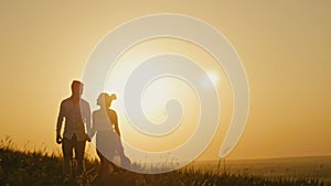 Loving couple - brave young man and beautiful girl at sunset silhouette, slow-motion