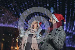 Loving couple burning sparklers by holiday illumination on new years eve