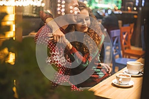 Loving couple in a cafe hug and drink cocoa