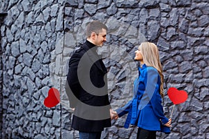 Loving couple in a coat with hearts on the gray background outd