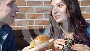 Loving couple cute talking and eating hamburgers in a cafe or at home