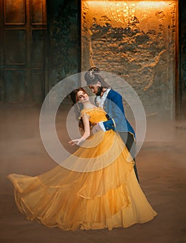 loving couple is dancing at fairy ball. Happy beauty woman fantasy princess in yellow dress and guy is enchanted beast