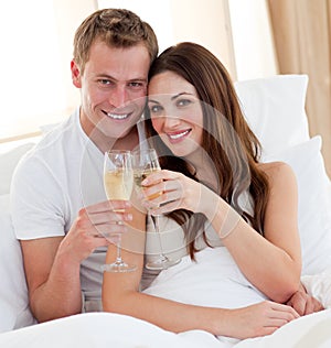 Loving couple drinking champagne lying in bed