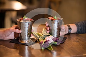 Loving couple drinking cocktails with metal cups and tulips on the table
