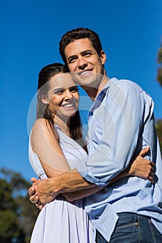Loving couple embracing each other against clear blue sky