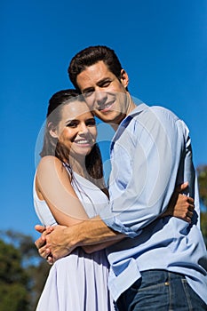 Loving couple embracing each other against clear blue sky