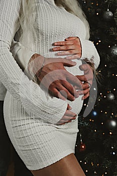 Loving couple embracing, the pregnant woman tenderly placing her hands on the stomach