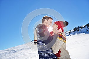 Loving couple embracing in winter park. They put colored caps and scarves.