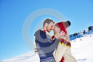 Loving couple embracing in winter park. They put colored caps and scarves.