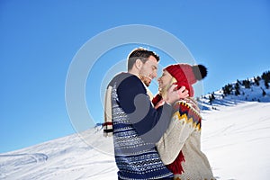 Loving couple embracing in winter park. They put colored caps and scarves.
