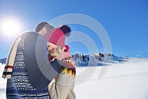 Loving couple embracing in winter park. They put colored caps and scarves.