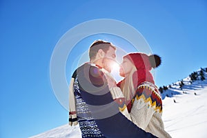 Loving couple embracing in winter park. They put colored caps and scarves.