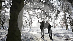 A loving couple in fairy-tale winter weather plays snowballs