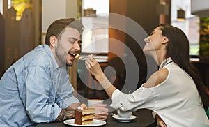 Loving Couple Feeding Each Other On Romantic Date In Cafe