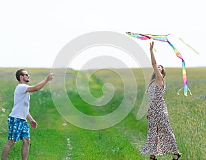 Loving couple are fling kite on a meadow