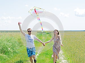 Loving couple are fling kite on a meadow