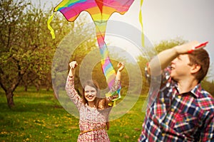 Loving couple are fling a kite on a spring meadow