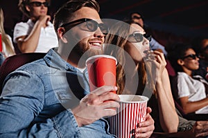 Loving couple friends sitting in cinema watch film