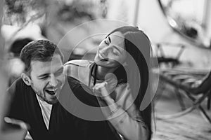 Loving couple. Girl hugs her boyfriend sitting in the cozy romantic cafe. Black and white photo