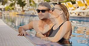 loving couple having fun together in holiday resort swimming pool. summer vacation