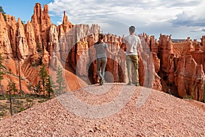 Loving couple holding hands with scenic aerial view of hoodoo sandstone rock formations on Queens Garden trail, Utah