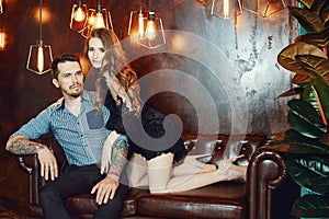 Loving couple hugging on the couch against the bright lights of lamps. Passion and tenderness, man and woman love each other. Girl
