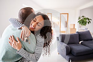 Loving Couple Hugging Holding Keys To New Home On Moving Day