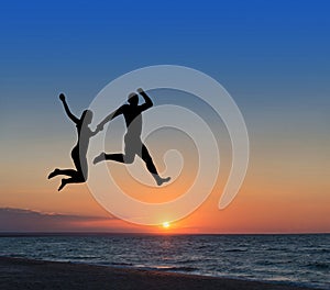 Loving couple jumping highly in the sky at beach resort