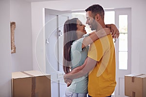 Loving Couple With Keys To New Home Hugging By Front Door On Moving Day