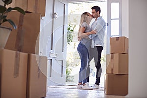 Loving Couple Kissing In Doorway As They Move Into New Home Together