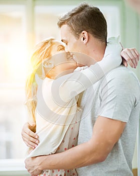 Loving couple kissing while hugging in house