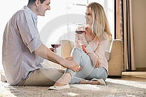 Loving couple looking at each other while drinking red wine at home